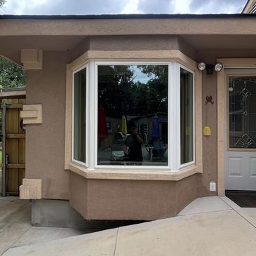 New bay window with a white frame installed in a stucco wall