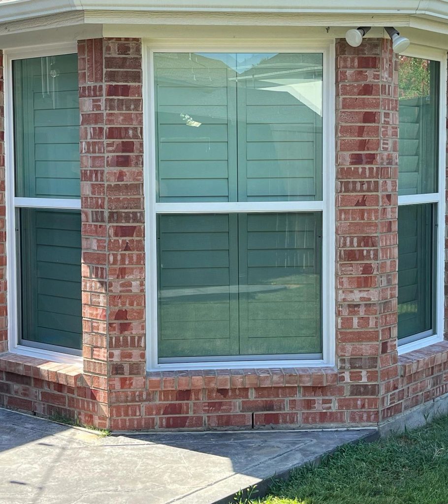 Single-hung windows with white vinyl frames in a brick bay wall